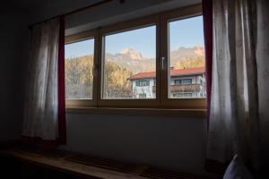 a window with a view of a house and mountains at Haus Berger in Bayrischzell