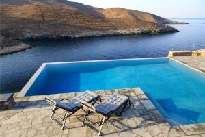 two chairs and a swimming pool with a view of the ocean at MV Kythnos in Agios Dimitrios