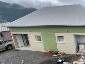 a green and white house with a car in front of it at Villa bienvenue in Bras des Calumets
