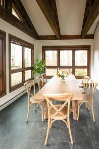 einen Holztisch und Stühle in einem Zimmer mit Fenstern in der Unterkunft Wooded Cottage in Elizabethtown with hot tub and sauna in Elizabethtown