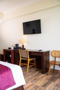 a hotel room with a bed and a desk with a television at D'girijati Resort And Beachclub in Girijati