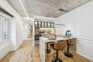 una cocina con paredes blancas y una gran isla con taburetes. en KAZA BELLA - Malakoff, en Malakoff