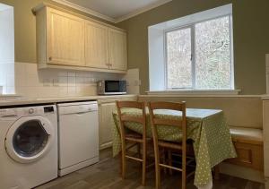 a kitchen with a table and a washing machine at Swiss Cottage in Ballindalloch