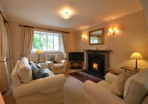 a living room with white furniture and a fireplace at Swiss Cottage in Ballindalloch +6 photos