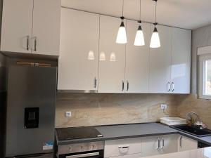 a kitchen with white cabinets and a black counter top at House Baltic KAMENO Herceg Novi in Herceg-Novi