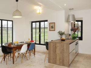 a kitchen and dining room with a wooden table and chairs at La Maison Aux Fleurs by La Boîte En Plus in Courteuil