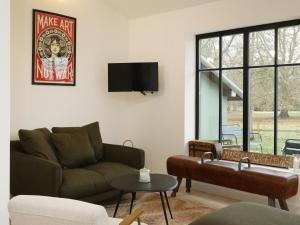 a living room with a couch and a flat screen tv at La Maison Aux Fleurs by La Boîte En Plus in Courteuil