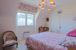 a bedroom with a bed and a window and a chandelier at Maison du pêcheur 150 m plages in Saint-Quay-Portrieux