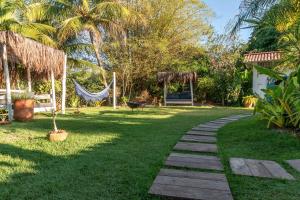 a walkway in a garden with a hammock and a yard at AWÊ Villa Boutique & Beach Club in Trancoso