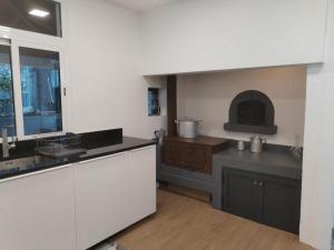 a kitchen with white cabinets and a sink and a stove at Avó Lucindinha House - Porto Moniz in Porto Moniz