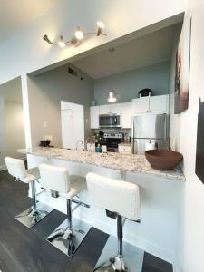 a kitchen with white chairs and a counter top at Yale Modern Downtown Chateau in New Haven