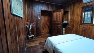 a bedroom with wood paneling and a bed and a door at Kemmiu Guest House Sao Tome in São Tomé