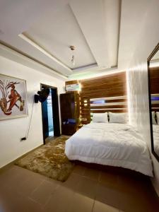 a bedroom with a white bed with a wooden headboard at Peridot Studio Apt maitama in Abuja