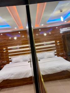 two beds in a room with a mirror at Peridot Studio Apt maitama in Abuja