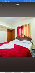 a hotel room with two beds with red sheets at Sri Sai Residency Ooty in Ooty +2 photos