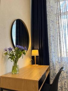 a vase of flowers on a table with a mirror at Comfort in Chernihiv
