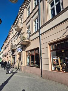 a woman walking down a street in front of a building at Five Rooms Piotrkowska 28 in Łódź