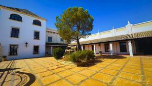 a courtyard in front of a white building with a tree at Palacio de la Canaliega in El Rocío