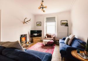 a living room with two blue couches and a tv at Harvieston in Elie