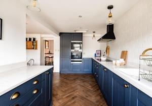 a kitchen with blue cabinets and white counter tops at Harvieston in Elie +28 photos