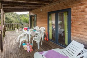 a table and chairs on the deck of a cabin at Camping Sole Di Sari in Sari Solenzara
