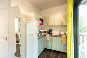 a kitchen with green cabinets and a white refrigerator at Camping Sole Di Sari in Sari Solenzara +41 photos