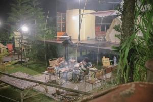 two people sitting at a table in a garden at night at Outing Camping เอาท์ติ้ง แคมป์ปิ้ง in Campson