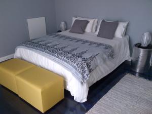 a bedroom with a large bed with a yellow stool at Garden Gate Guest House in Port Elizabeth