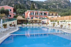 a large swimming pool with white chairs and buildings at Maria Studios in Paleokastritsa