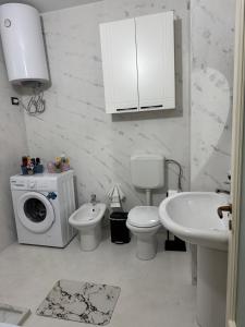 a bathroom with a toilet sink and a washing machine at Ralph Apartments in Vlorë
