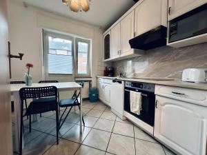 a kitchen with white cabinets and a table with a chair at City Apartment Rheine Zentral & Kliniknah in Rheine