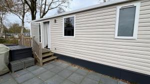 a white house with a porch and a window at Chalet Jupp in Lauwersoog