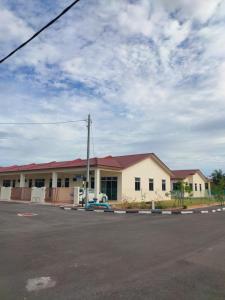 a white building with a red roof on a street at Puteri Homestay in Kangar