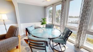 a dining room with a glass table and chairs at Surf and Turf in Folly Beach