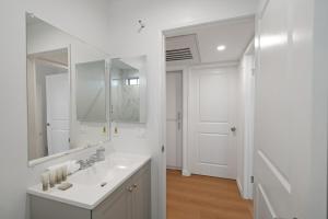 a white bathroom with a sink and a mirror at 2BR Plus Bonus Room with Pool Access Near Universal Studios in Los Angeles +14 photos
