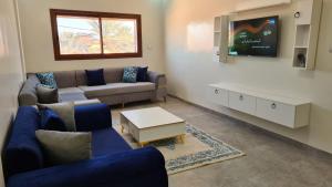 a living room with a couch and a tv at Al Yasmine residence in Douz