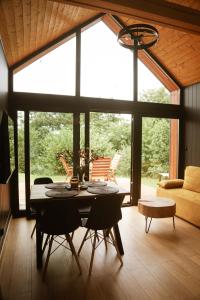 a dining room with a table and chairs in a living room at Black & White Cekcyn Bory Tucholskie in Cekcyn +9 photos
