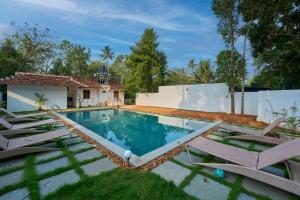 une piscine avec des chaises longues et une maison dans l'établissement Ananda Marari Heritage Villa, à Alappuzha