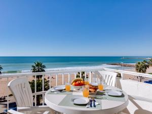 a table with a bowl of fruit on a balcony with the beach at Canto do Mar in Quarteira