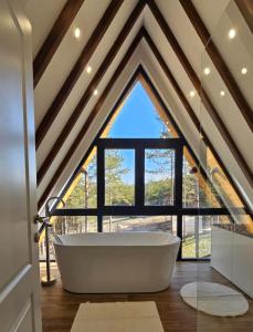 a white bath tub in a room with a large window at Planinska kuća Homey in Zlatibor