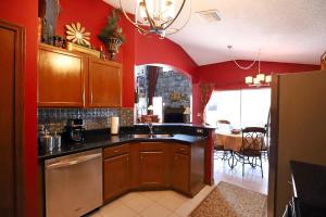 a kitchen with red walls and a sink and a table at Waterfront 6-Bedroom Wizarding Villa in Lake Berkley Near Universal Studio's Harry Potter in Kissimmee