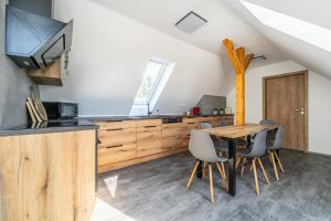 a kitchen and dining room with a wooden table and chairs at Podkrovní apartmán Studnice in Nové Město na Moravě