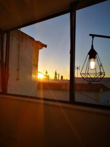 een uitzicht op de zonsondergang vanuit een raam met een lamp bij Casa da Vila in Ferragudo