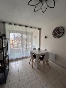 una sala da pranzo con tavolo, sedie e una finestra di Appartement à ARGELES SUR MER PLAGE ad Argelès-sur-Mer