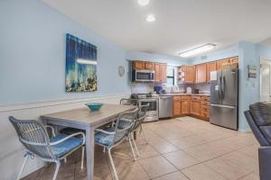 a kitchen with a table and chairs and a refrigerator at Sandpiper 1C- Stylish Gulf-side affordable in Gulf Shores +23 photos