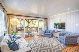 a living room with a couch and chairs and a television at Knysna Lagoon - Lakeview Haven Chalet in Knysna