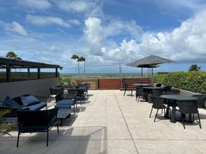 Un patio con mesas y sillas y una sombrilla. en Bela Hospedagem - #Unity Flats Cabo Branco, en João Pessoa