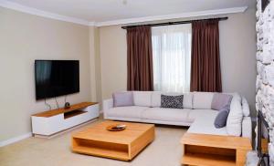 a living room with a white couch and a flat screen tv at Olive Branch Resort in Kas