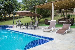 a pool with chairs and a table with an umbrella at Sitio and Beach Tennis in Itatiba