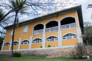 a yellow and white house with a stone wall at Sitio and Beach Tennis in Itatiba